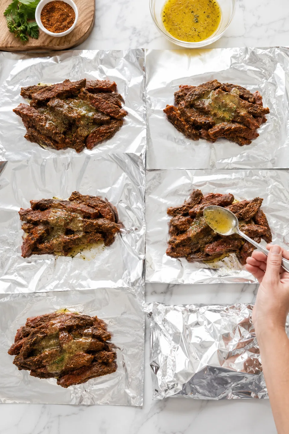 Seasoned steak being portioned onto sheets of aluminum foil