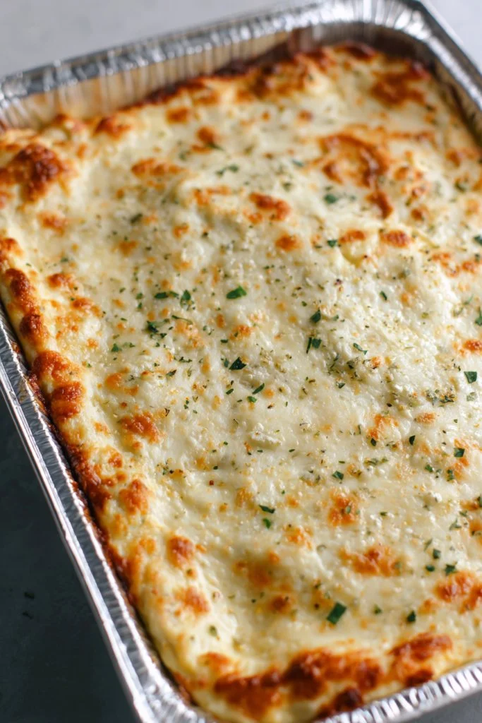 Delicious cheesy garlic herb dip served in a bowl with herbs and crackers around