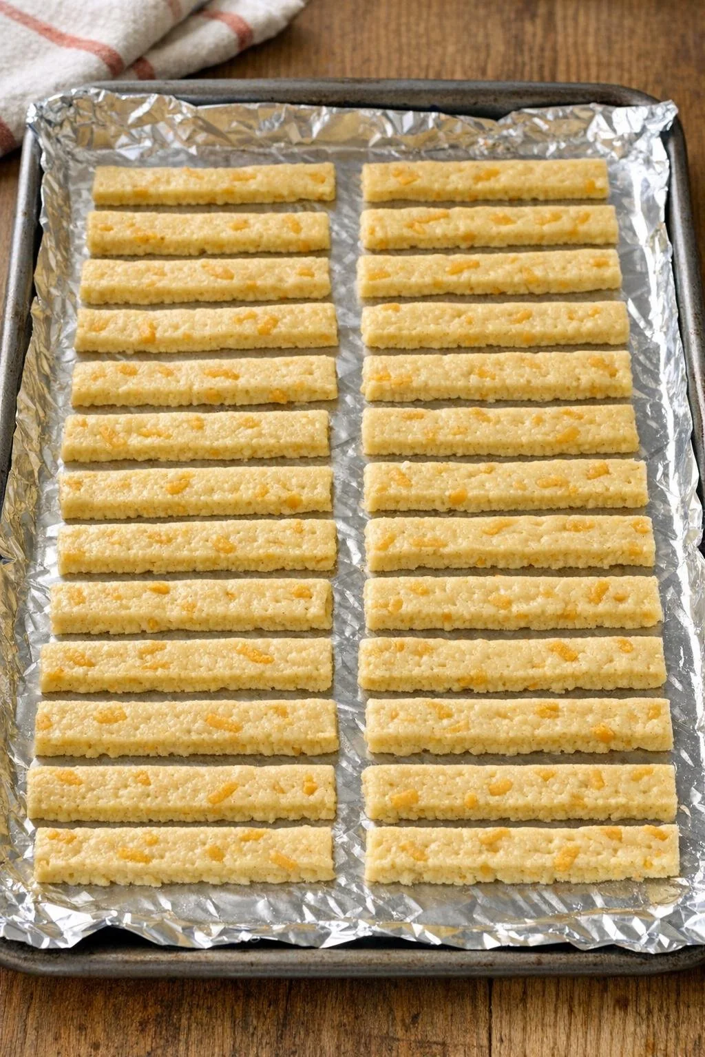 Cut strips of cheddar biscuit dough arranged on a lined baking tray