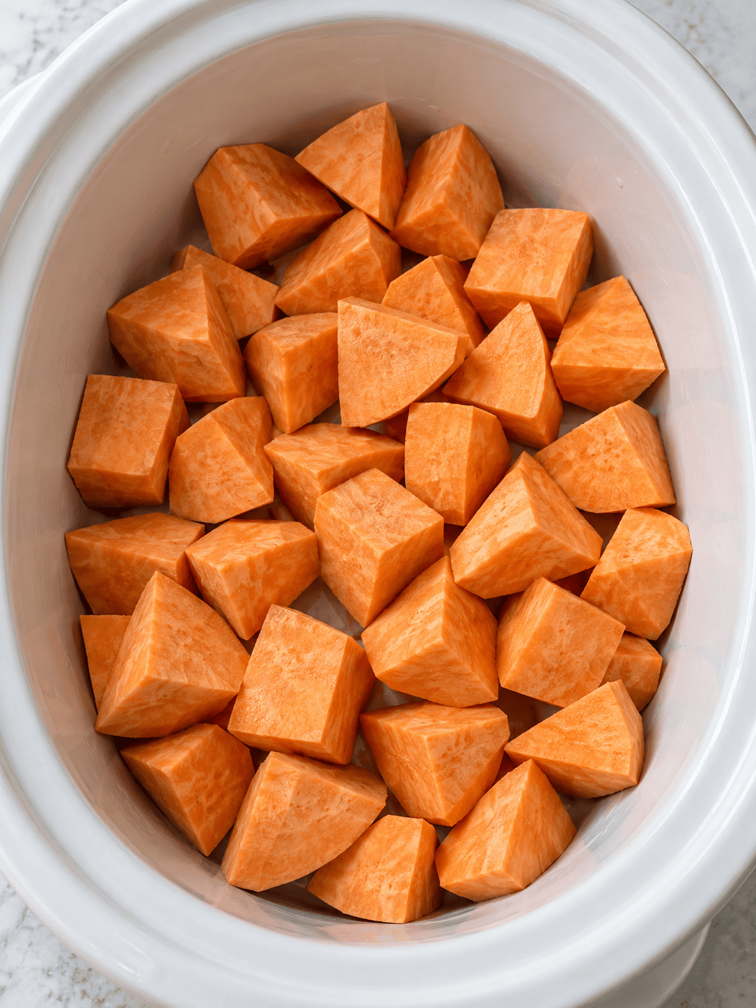 Chunks of sweet potato spread across the bottom of a slow cooker