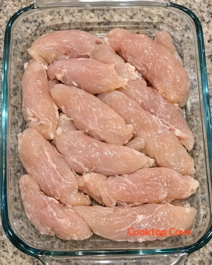 Raw chicken tenderloins in a glass casserole dish with additional ingredients