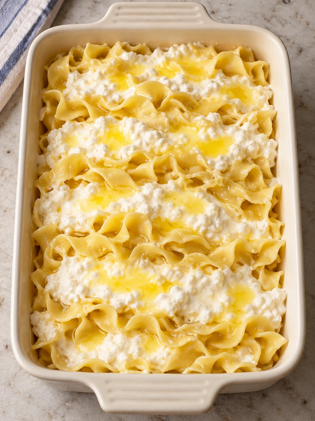 Unbaked egg noodles layered with sour cream cottage cheese and butter
