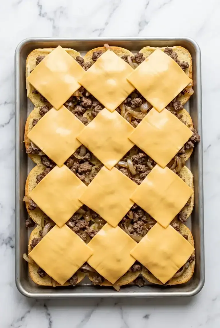 Cheese slices melting over beef on a sheet pan