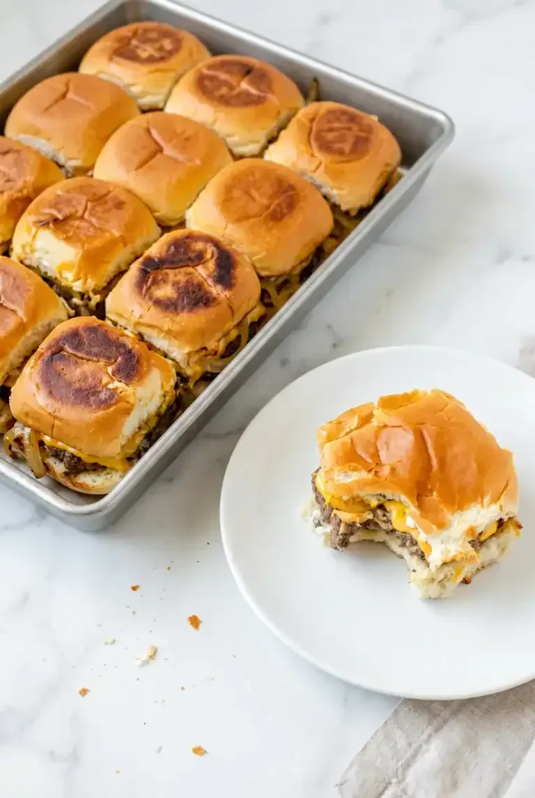 Tray of baked sliders with one cheeseburger served on a plate