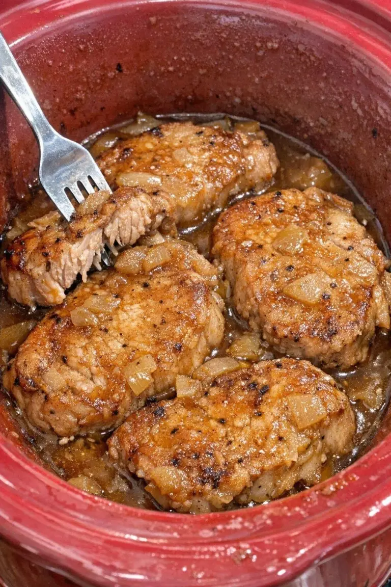 Slow cooker apple cider pork chops garnished with herbs, ready to serve.