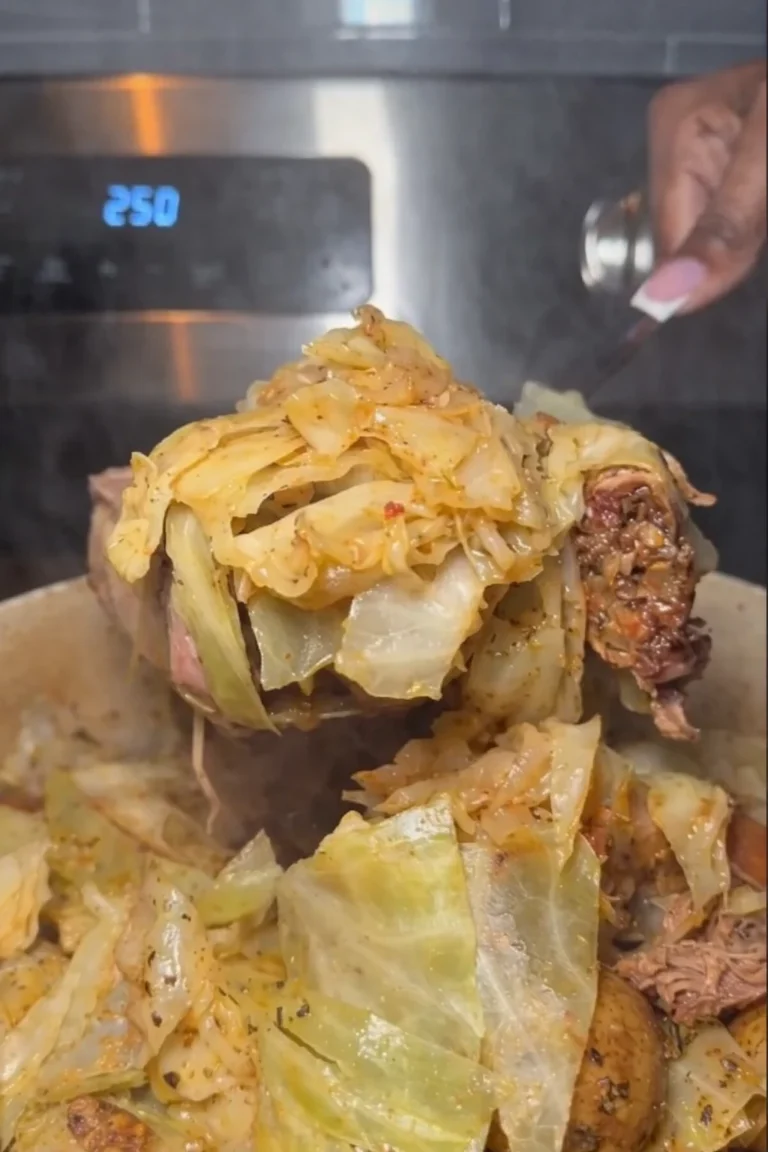 A vertical close-up shot of a steaming Dutch oven filled with a smoked turkey cabbage roast. Thick, tender wedges of pale green cabbage are layered over succulent, dark smoked turkey wings. The cabbage is glistening with a buttery, savory broth and seasoned with black pepper and herbs. A hand is seen in the background using a large spoon to serve a portion.